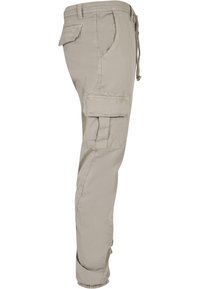 Beige cargo kalhoty s bočními kapsami, elastickými manžetami a stahovacími šňůrkami v pase. Odolná, lehká tkanina s hladkým povrchem.