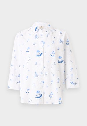 Chemise blanche à manches longues avec col et boutons, présentant un délicat motif floral bleu et de petits détails ajourés sur tout le tissu.