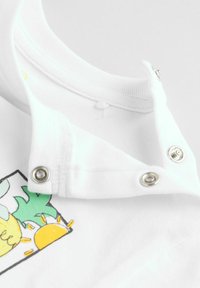 Witte katoenen T-shirt met een drukknoopsluiting bij de kraag, met een kleurrijke ananas- en zonafbeelding. Zachte textuur, korte mouwen.