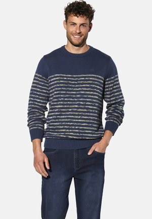 Navy blue sweater with horizontal stripes in yellow and cream; ribbed crew neck and cuffs; textured knit. Paired with dark denim jeans.