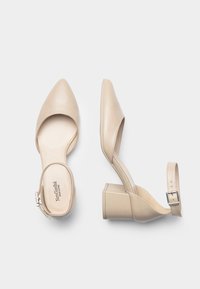 Scarpe con tacchi alti in pelle beige, con punta affusolata, cinturino alla caviglia e tacco spesso. Texture liscia e design minimalista.