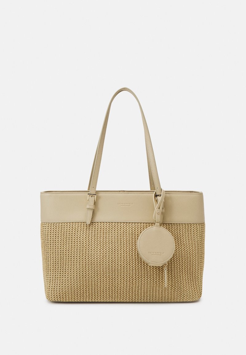 Sac cabas beige avec une section inférieure tissée et une section supérieure lisse. Dispose de longues anses et d'une étiquette ronde détachable.
