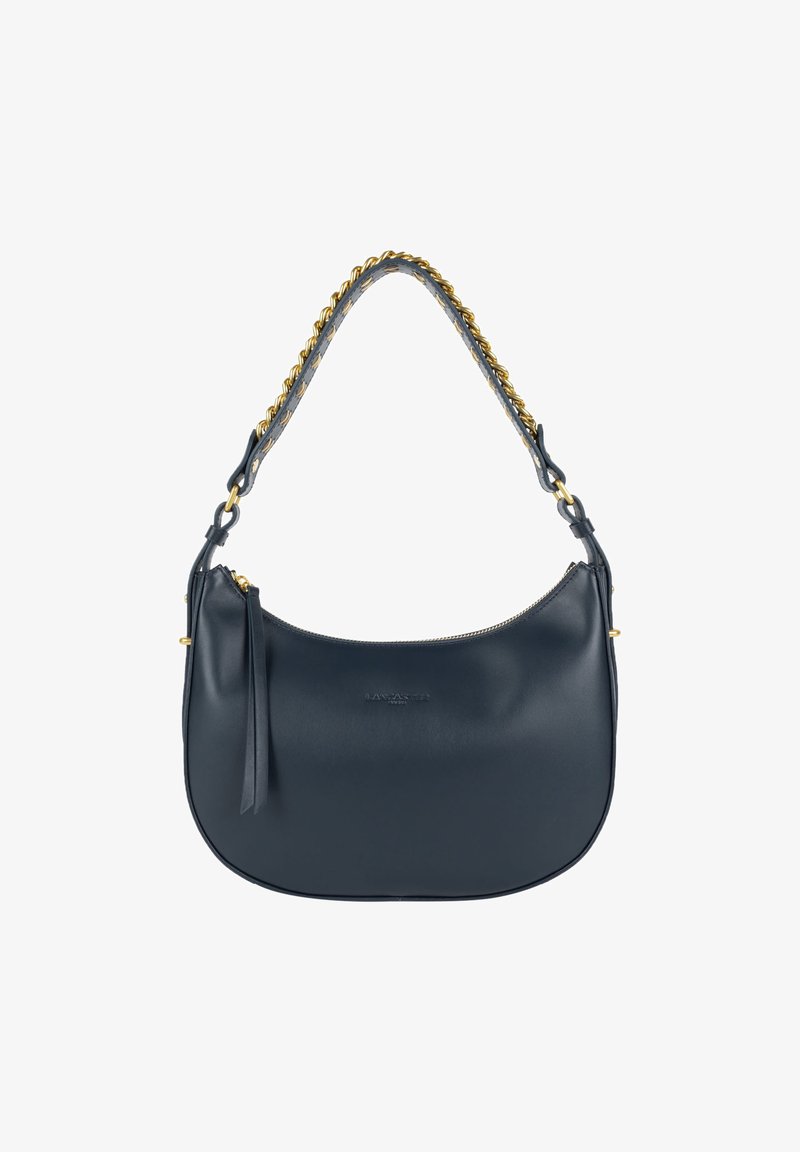 Sac en cuir marine à forme arrondie, avec une chaîne dorée et une fermeture éclair. Caractéristiques d'un détail en frange et d'un logo en relief sur le devant.