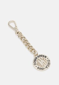 Srebrny metalowy brelok z łańcuszkiem i okrągłym zawieszką z wycięciami, wytłoczonym tekstem i zapięciem.