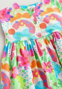 Robe en coton colorée avec un corsage à boutons, présentant divers motifs abstraits dans les teintes rose, orange, jaune, vert et bleu. Texture douce, jupon froncé.
