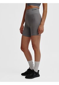 Grijze sportshorts met een geribbeld patroon, hoge tailleband en logo-detail. Draagt witte sokken en zwarte sneakers.
