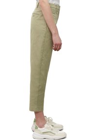 Lichtgroene katoenen chinos met een rechte snit, cropped kuitlengte en achterzakdetails, gecombineerd met witte en lichtgroene sneakers.