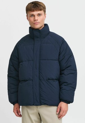 Navy puffer jacket with a high collar, quilted design, and elastic cuffs. Features front pockets and a relaxed fit. Textured fabric surface.