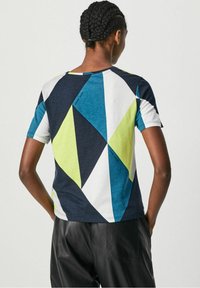 T-shirt z krótkim rękawem z geometrycznym wzorem w kolorze granatowym, turkusowym, limonkowym i białym. Miękki materiał, luźny krój i okrągły dekolt.