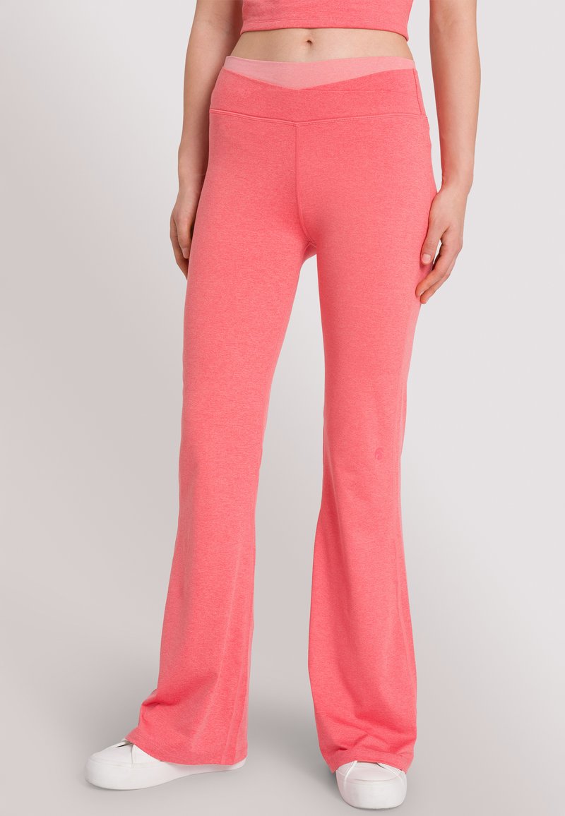 Fitted flare-pantalon van felroze elastische stof. Heeft een brede tailleband en een gladde textuur. Gemaakt in combinatie met witte schoenen.