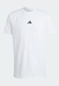 Bílé sportovní tričko s krátkým rukávem, s jemnou vzorovanou texturou a malým černým logem Adidas umístěným na hrudi.