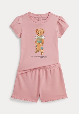 Różowy dwuczęściowy zestaw dla malucha z bluzką z krótkimi bufkami, ozdobioną ilustracją ubranego misia, i pasującymi marszczonymi szortami.