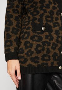 Leopardprint cardigan in bruin en zwart breiwerk, met zilveren knopen en een voorzak, voorzien van ribboorden en zoom.