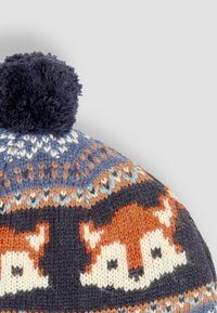 Knit beanie with a navy pom-pom, featuring fox motifs in orange and white, with intricate patterns in blue and brown tones.