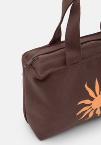 Borsa di tela marrone con cerniera, caratterizzata da un design solare arancione. Ha due manici in tessuto per un facile trasporto.