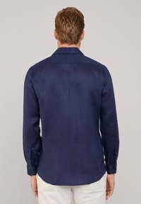 Camisa de manga larga azul marino en mezcla de lino, con un collar estándar y puños abotonados, de textura suave y un ajuste ligeramente entallado.