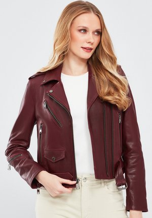 Giubbotto da biker in pelle bordeaux con zip argentate, design asimmetrico e tasche con bottoni. Vestibilità slim e texture liscia.