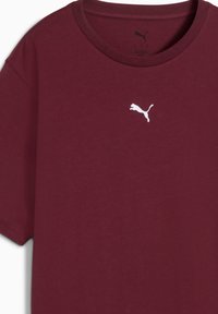 T-shirt in cotone bordeaux con maniche corte e scollo rotondo. Presenta un piccolo logo Puma bianco sul petto. Texture morbida.