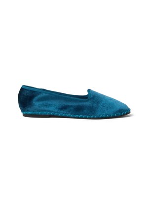 Zapato plano tipo slip-on en terciopelo azul con punta redondeada y ribete cosido a lo largo de la suela, fotografiado sobre un fondo blanco.