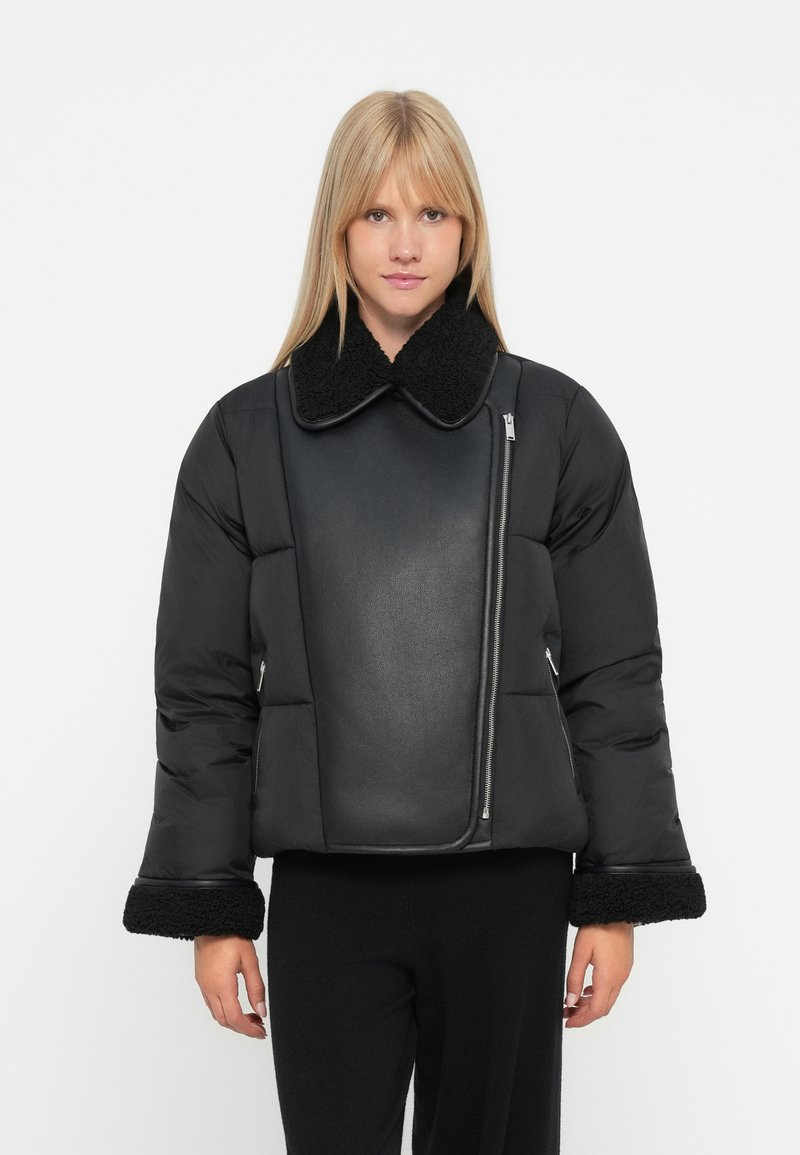 Svart puffjakke med faux shearling krage og mansjetter, med en blank lærpanel og asymmetrisk glidelåslukking.