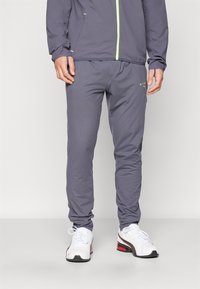 Grijze sportbroek van lichtgewicht materiaal, met een slim fit, elastische tailleband en discreet merk in neon groen.