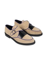 Beżowe zamszowe buty z czarnymi plisami i fioletowym wykończeniem. Posiadają szeroki pasek z srebrną klamrą i płaską czarną podeszwę.