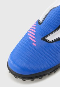 Μπλε αθλητικό παπούτσι με υφασμάτινο επάνω μέρος, ροζ διακοσμητικές ρίγες και μαύρη λαστιχένια σόλα. Διαθέτει αεροδυναμικό σχεδιασμό και ενισχυμένη περιοχή στη μύτη.