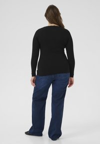 Black long-sleeve ribbed top paired with blue wide-leg jeans, showcasing a simple design and soft texture. The shirt has a round neckline.