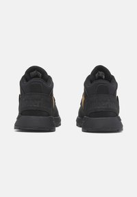 Baskets Timberland noires et brunes avec une tige texturée, un col rembourré et une semelle en caoutchouc épaisse, avec un détail du logo au niveau du talon.