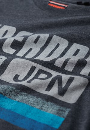 Donkergrijze katoenen t-shirt met grote witte tekst "SUPERDRY" en "JPN" met gestructureerde blauwe en grijze gestreepte accenten.