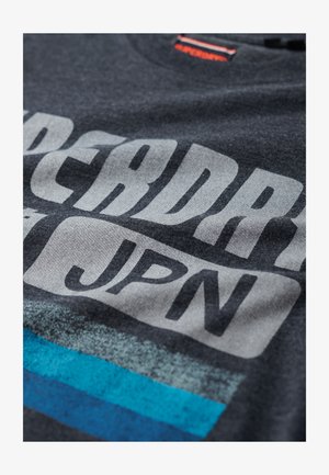 Donkergrijze katoenen t-shirt met grote witte tekst "SUPERDRY" en "JPN" met gestructureerde blauwe en grijze gestreepte accenten.