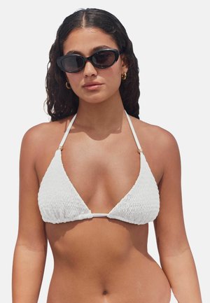 Bikini triangle blanc avec un tissu texturé, des fines bretelles et de petites accents en or reliant le haut. Matière lisse et respirante.