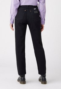 Czarne dżinsy o prostym kroju, z dwoma tylnymi kieszeniami i małą skórzaną metką. Posiadają szlufki na pasek i delikatne wyblaknięcie koloru.