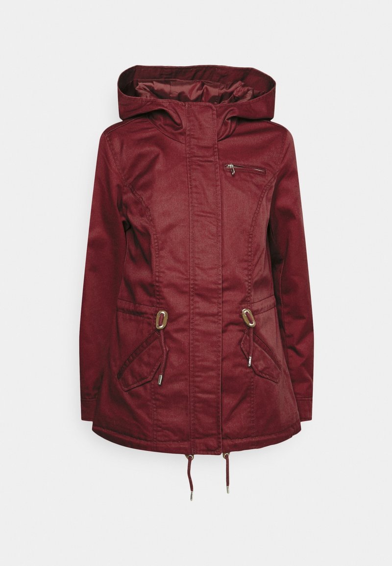 Veste à capuche couleur bordeaux avec une texture lisse, poche zippée, taille à cordon de serrage et deux poches avant, ornée d'accents métalliques.