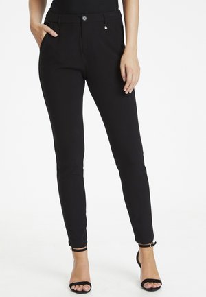 Pantaloni neri attillati con una texture liscia, dotati di chiusura a bottone, tasche laterali e un piccolo emblemma dorato sopra la tasca destra.