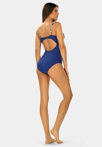 Granatowy jednoczęściowy strój kąpielowy z kwiatowymi ramiączkami; charakteryzuje się odkrytymi plecami i gładką teksturą. Zapewnia komfort i swobodę ruchów w wodzie.