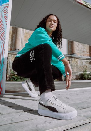 Puma platform sneakers in light gray suede with black accents, white sole, and textured laces. Platform height approximately 2 inches.