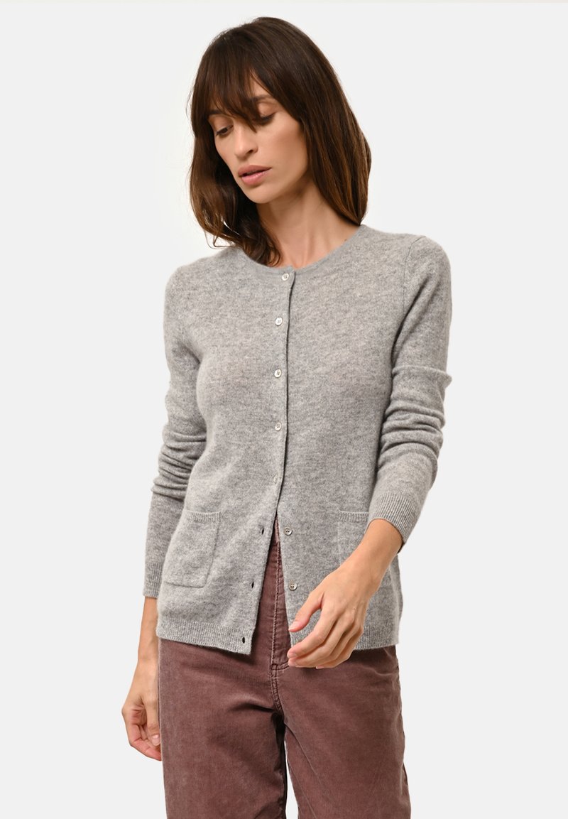 Šedý kardigan z měkké tkaniny, s kulatým výstřihem, dlouhými rukávy, zapínáním na knoflíky a dvěma předními kapsami.