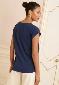 Camicia a maniche corte blu navy con risvolti, tessuto morbido e vestibilità rilassata. Presenta un design minimalista, adatta per un abbigliamento casual.