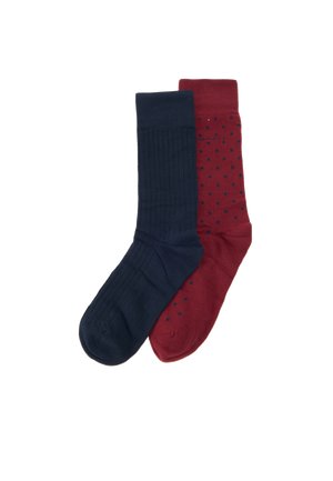 Une paire de chaussettes : l’une est unie bleu marine, l’autre est bordeaux à pois bleu marine, sur fond blanc.