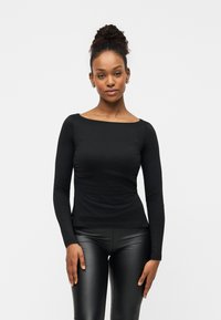 Μαύρο πουκάμισο με μακριά μανίκια και λαιμόκοψη τύπου βαρκούλα, κατασκευασμένο από λείο ύφασμα. Διαθέτει εφαρμοστή γραμμή και ανοίγματα στα πλάγια στο τελείωμα.