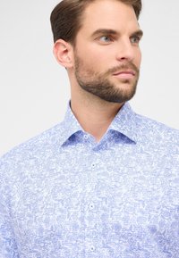 Lichtblauwe button-up shirt met een bloemmotief in een donkerder blauw, vervaardigd uit een gladde stof met een gestructureerde kraag en zichtbare knopen.