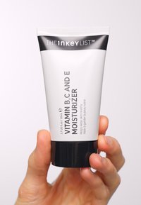 Vitamingrönsaker B, C och E fuktkräm i en vit tub med svart botten. Innehåller produktnamn och detaljer tryckta i fet svart text.