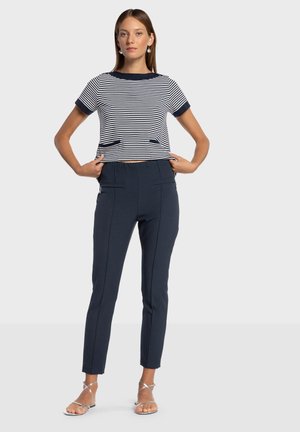 Top de manga corta a rayas con acentos en azul marino, combinado con pantalones ajustados azul marino que presentan bolsillos laterales y detalles de costura limpia.