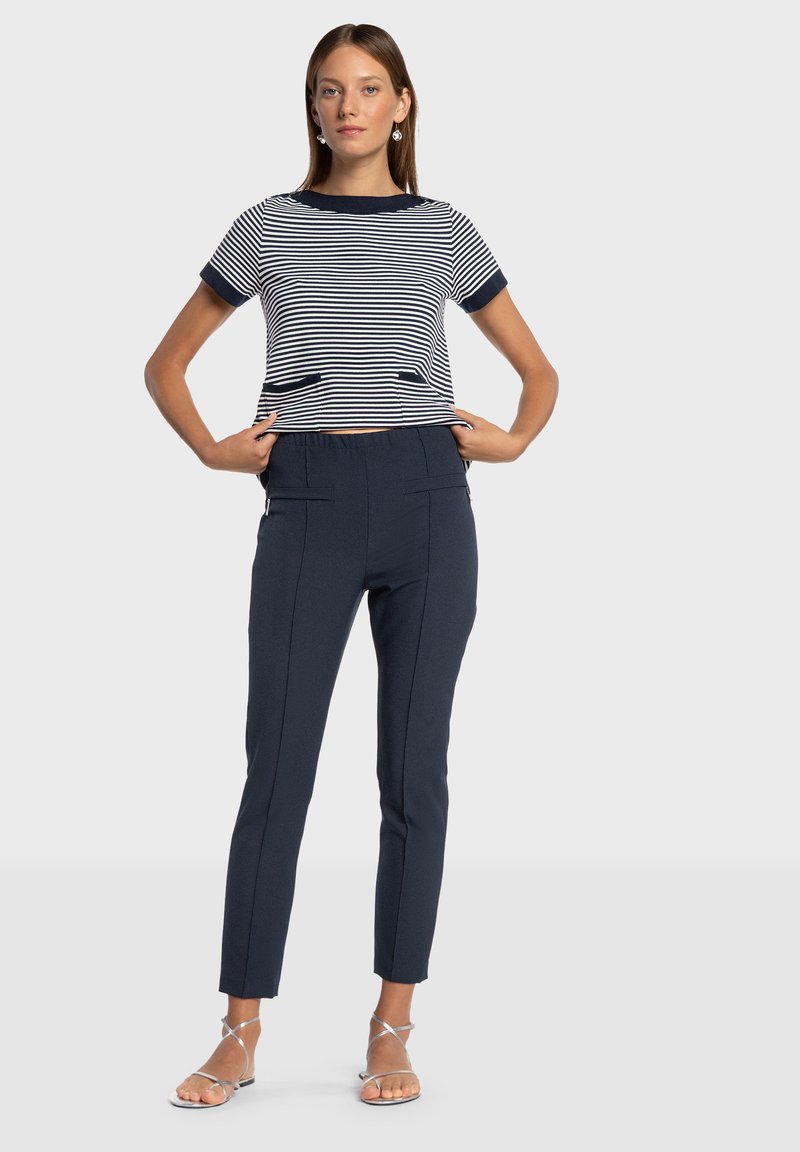 Gestreepte top met korte mouwen en marineblauwe accenten, gecombineerd met marineblauwe nauwsluitende broek met zijzakken en nette stikdetails.