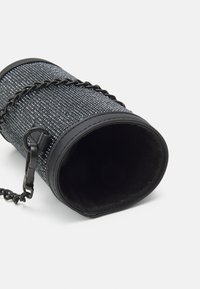 Borsa cilindrica nera con un'esterno testurizzato e scintillante. Presenta una tracolla in catena nera, un'apertura rotonda e un rivestimento interno morbido.