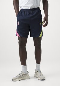 Tengerészeti stílusú sportnadrág rózsaszín és neon zöld részletekkel, rugalmas derékkal, oldalsó zsebekkel és hímzett logóval a bal combon.