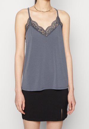 Camisole grise avec une dentelle au niveau du col, des bretelles ajustables et une coupe décontractée, assortie d'une mini jupe noire avec une fente sur le côté.