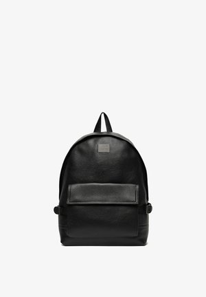 Schwarzer Leder-Rucksack mit Frontklapptasche, Top-Griff und verstellbaren Seitenträgern vor weißem Hintergrund.