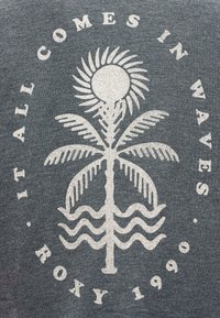 Λευκό γραφικό με στυλιζαρισμένο ήλιο, φοίνικα και κύματα με το κείμενο "Όλα έρχονται σε κύματα" και "Roxy 1990" σε γκρι υφασμάτινο φόντο.